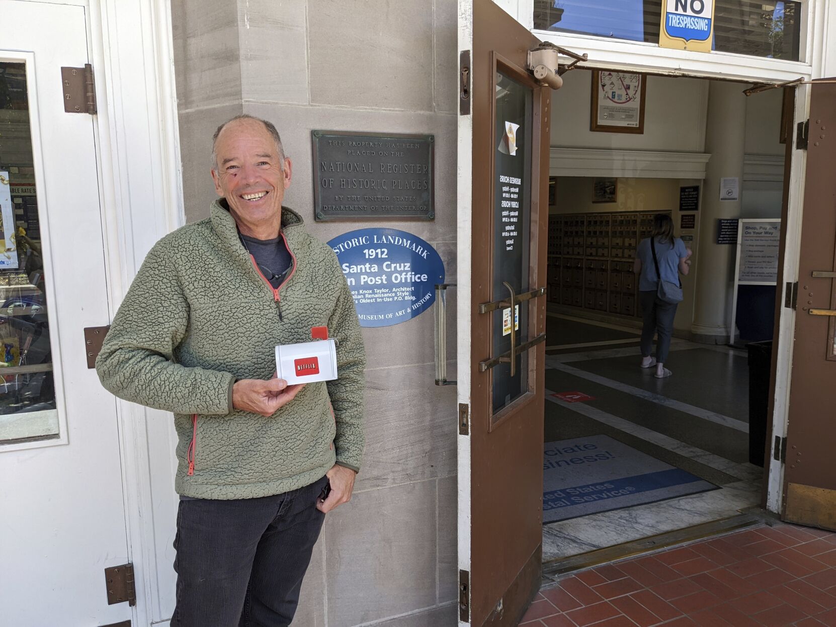 <p>Netflix co-founder or original CEO Marc Randolph stands outside the Santa Cruz, California post office where in 1997 he mailed a Patsy Cline CD to determine whether a disc could make it through the Postal System without being damaged, May 31, 2022 in Santa Cruz, Calif. He is holding a small mailbox that Netflix made in its early days to promote the DVD-by-mail rental service. (AP Photo/Michael Liedtke)</p>