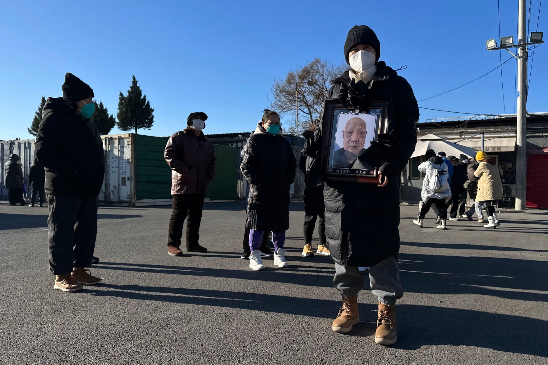 <p>A family member carries the photo of a deceased relative Dec. 17 outside a crematorium in Beijing.</p>