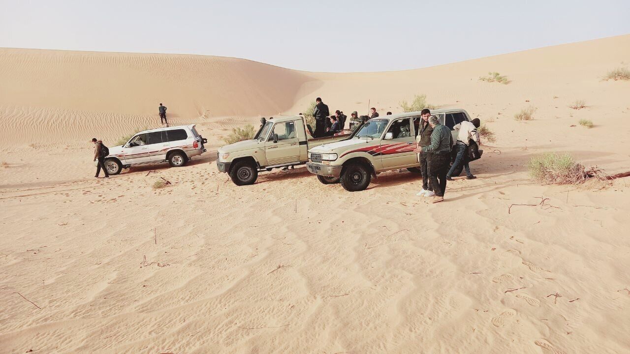 <p>Syrian Kurdish migrants wait for cars to arrive at a meeting point in a desert near the Libyan-Algeria border March 28 in the town of Debdeb, Algeria.</p>