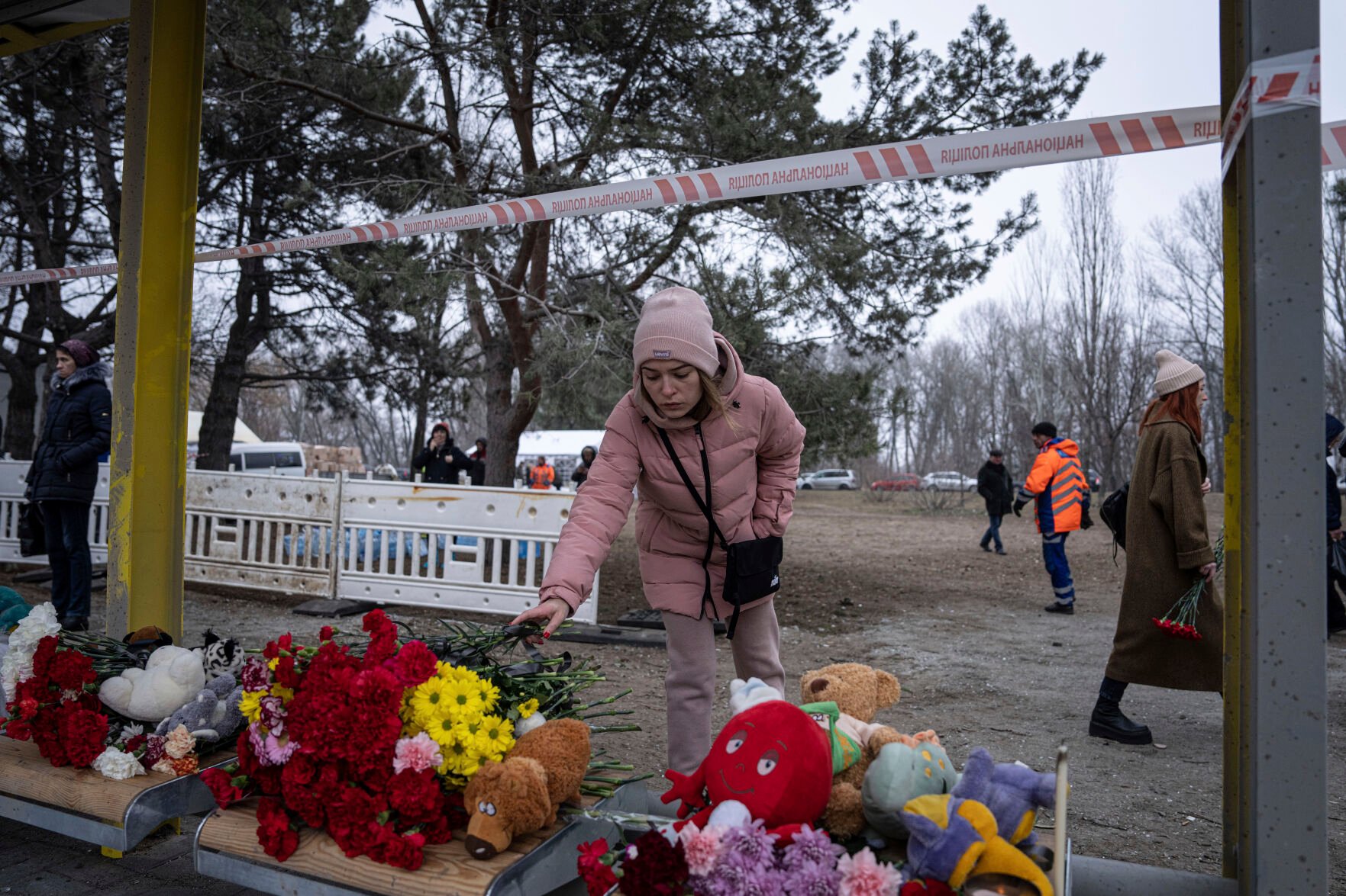 <p>A woman lays flowers Monday at a bus stop, in memory of people who were killed in a Russian missile strike on an apartment building Saturday in the southeastern city of Dnipro, Ukraine.</p>