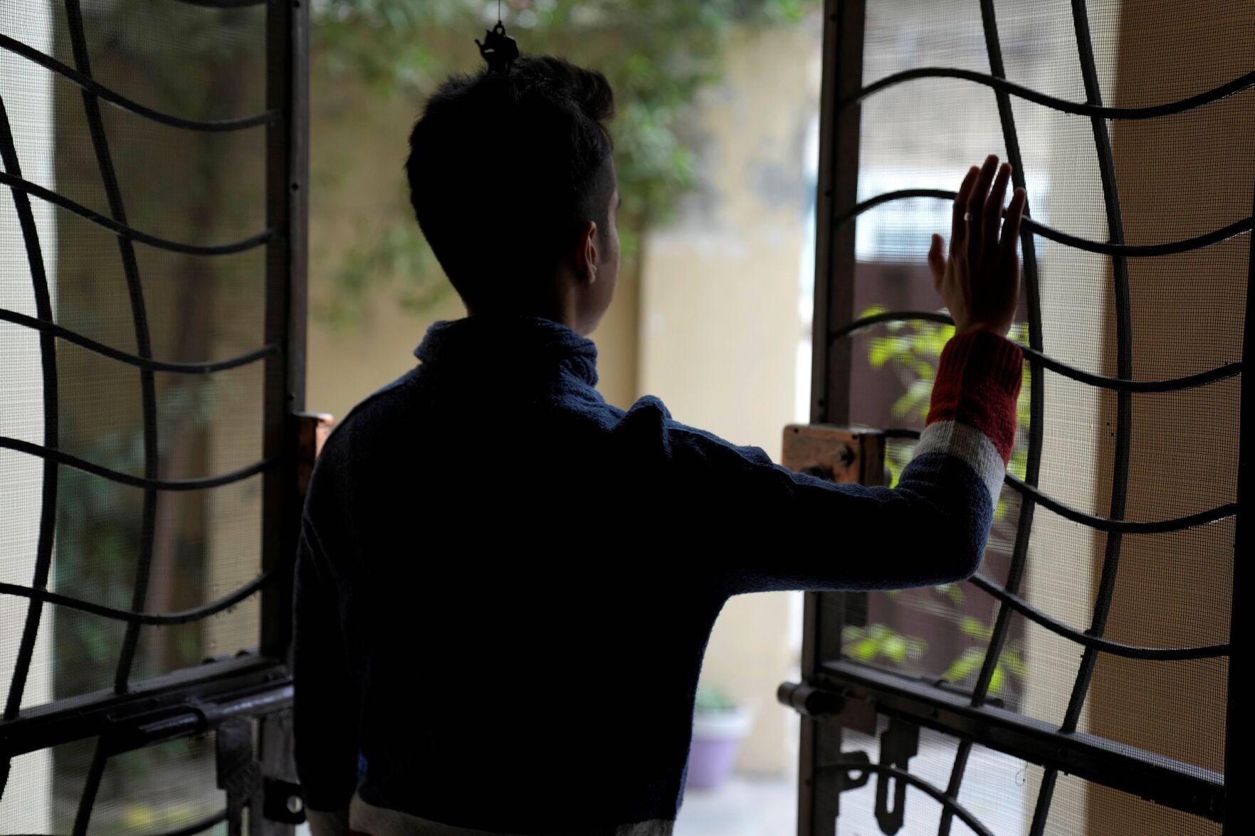 <p>Pakistani trans man Aman, who asked not be identifiable in the photo, looks out at his home after an interview with The Associated Press, on Dec. 2, 2022, in Lahore, Pakistan. </p>