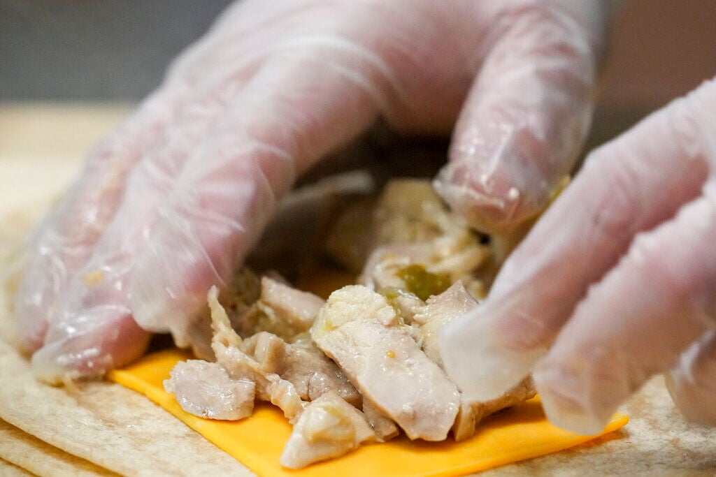 <p>Gavino Webb prepares whole wheat pollo verde flautas for Mount Diablo High School students to try during a taste test in Concord, Calif., Friday, Jan. 13, 2023. </p>