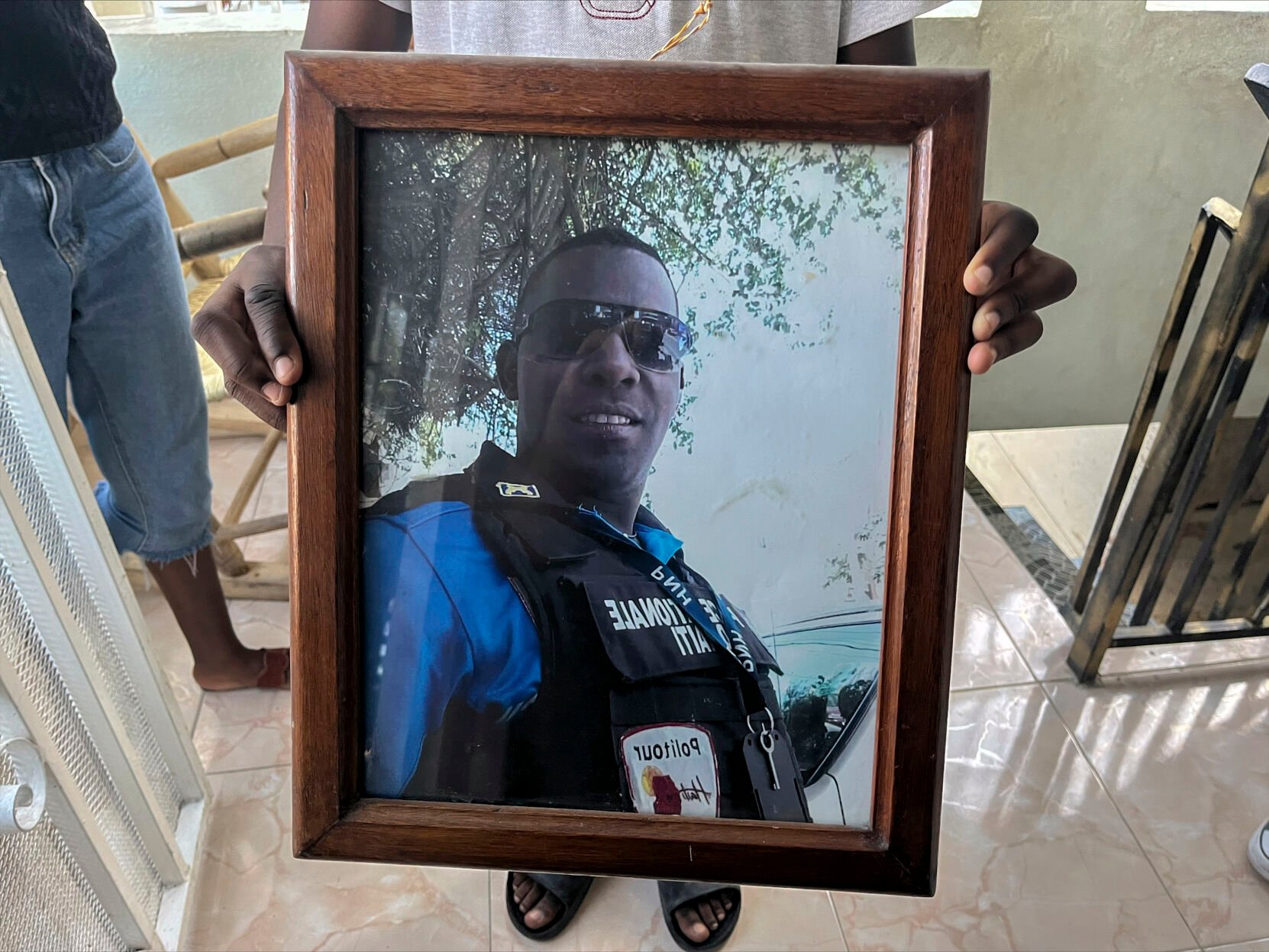 <p>A photo of missing Haitian police Officer Ricken Staniclasse is held by his 11-year-old son on Saturday at their home in Port-au-Prince, Haiti,</p>