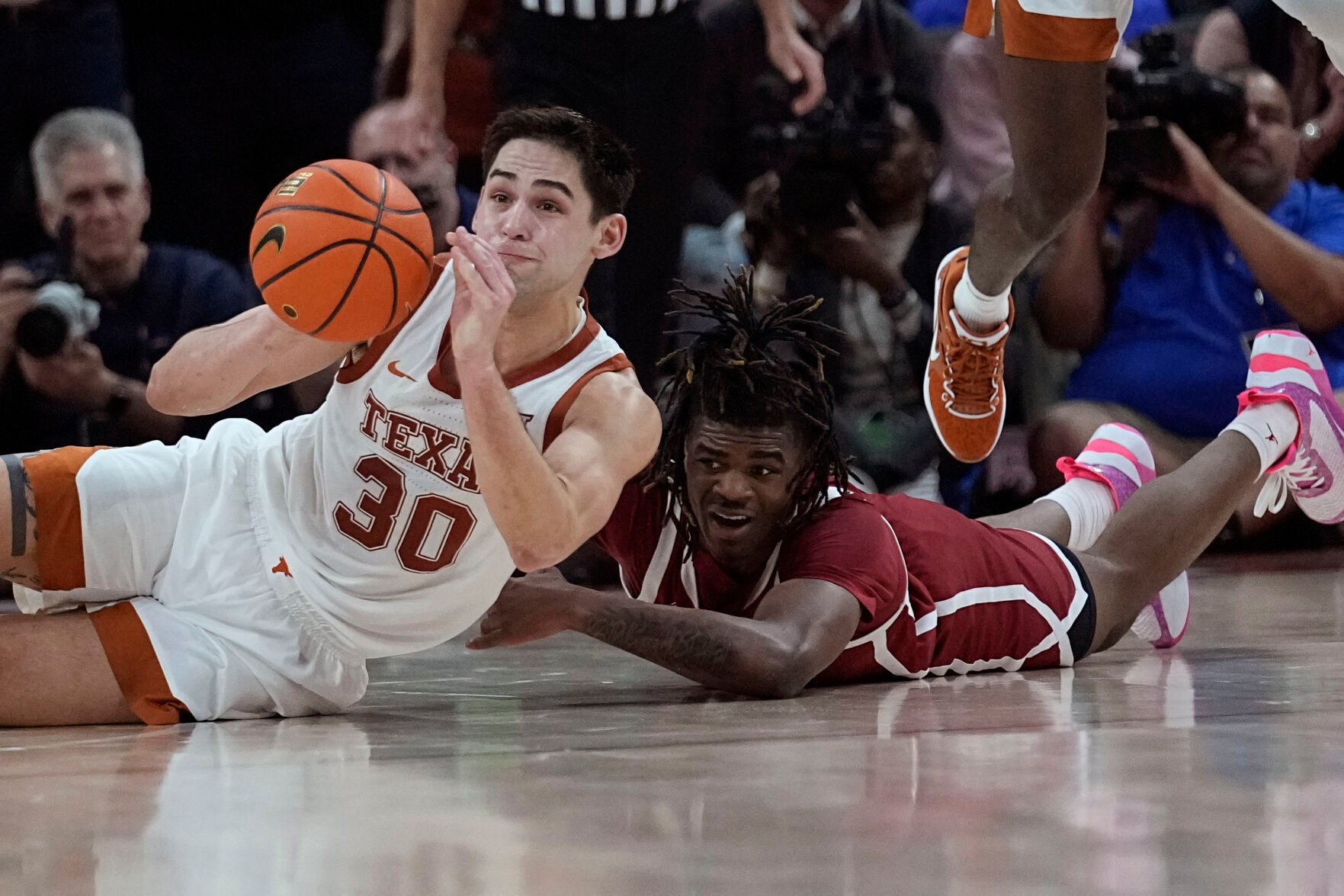 <p>Texas forward Brock Cunningham and Oklahoma guard Otega Oweh, right, scramble for the ball during overtime of Saturday's game in Austin, Texas.</p>