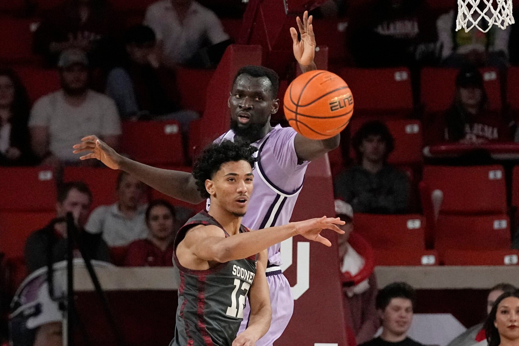 <p>Oklahoma guard Milos Uzan, fromt, passes in front of Kansas State center Abayomi Iyiola in the first half of Tuesday's game in Norman, Okla.</p>