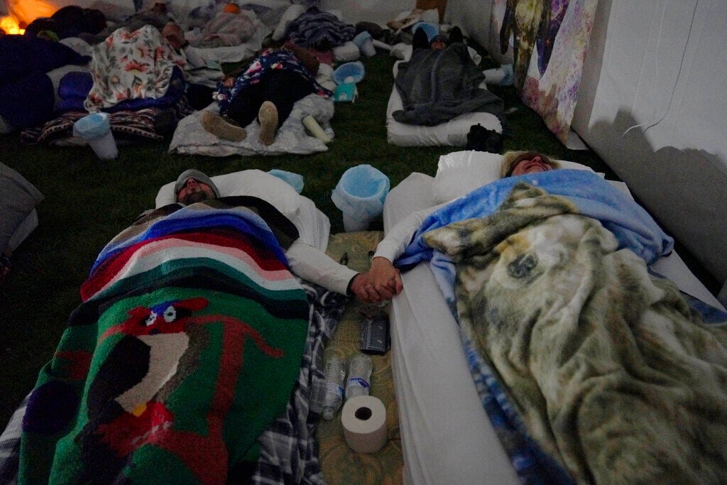 <p>Diwaldo and Mileidys Salado hold hands during a breathwork session at Hummingbird Church's ayahuasca retreat in Hildale, Utah, on Saturday, Oct. 15, 2022. Some sobbed uncontrollably during the session, which included rhythmic exhaling and inhaling set to a feel-good soundtrack that included "You Raise Me Up" by Josh Groban. They finished with a group scream. </p>