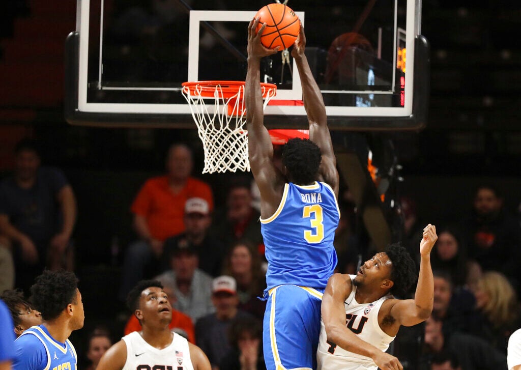<p>UCLA forward Adem Bona, center, dunks as Oregon State guard Dexter Akanno, right, defends during the first half of Thursday's game in Corvallis, Ore.</p>