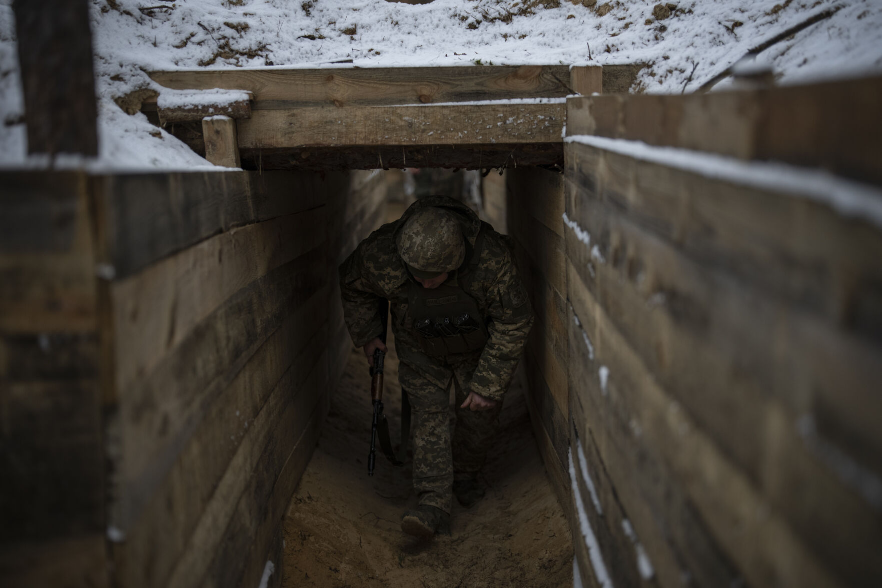 <p>A Ukrainian serviceman walks through a trench Feb. 1 at a position close to the border with Belarus, Ukraine.</p>