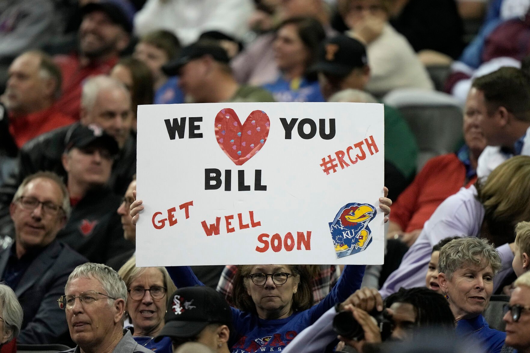 <p>A fan holds up a get well sign for Kansas head coach Bill Self during the first half of Thursday's basketball game against West Virginia.</p>