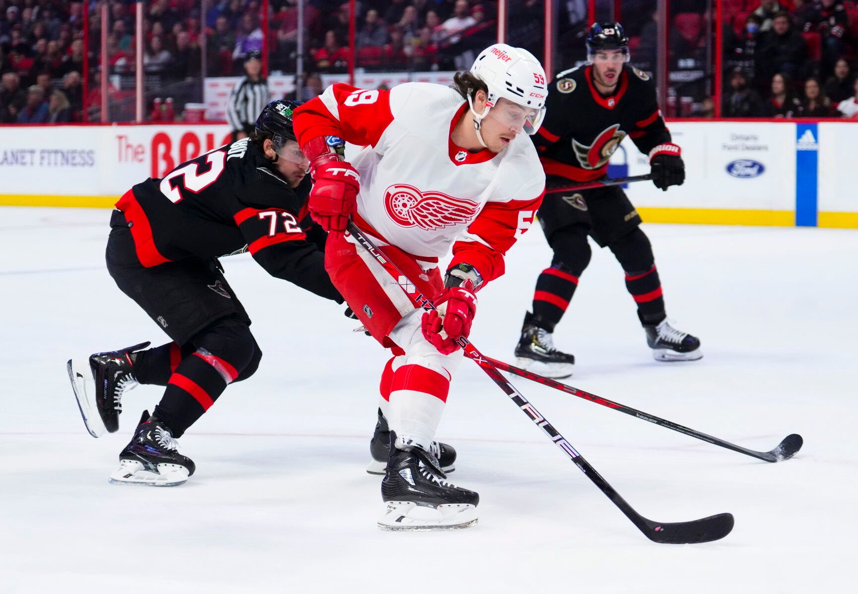<p>Detroit Red Wings left wing Tyler Bertuzzi, center, skates with the puck toward the net as Ottawa Senators defenseman Thomas Chabot, left, tries to push him off it during first-period of Monday's game in Ottawa, Ontario.</p>