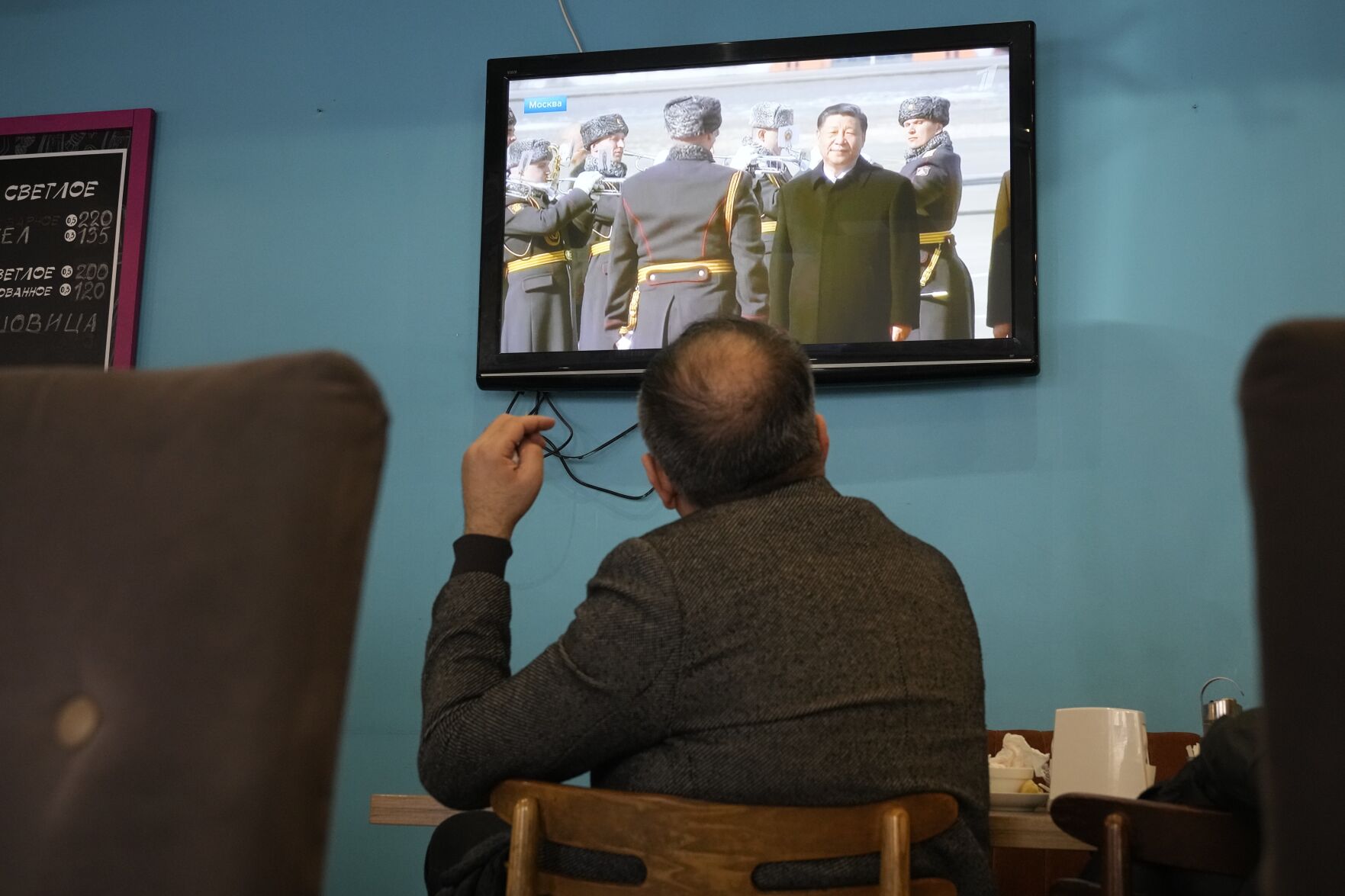 <p>A TV screen displays Chinese President Xi Jinping attending an official welcome ceremony upon his arrival at the Vnukovo-2 government airport outside Moscow, in a cafe Monday in St. Petersburg.</p>