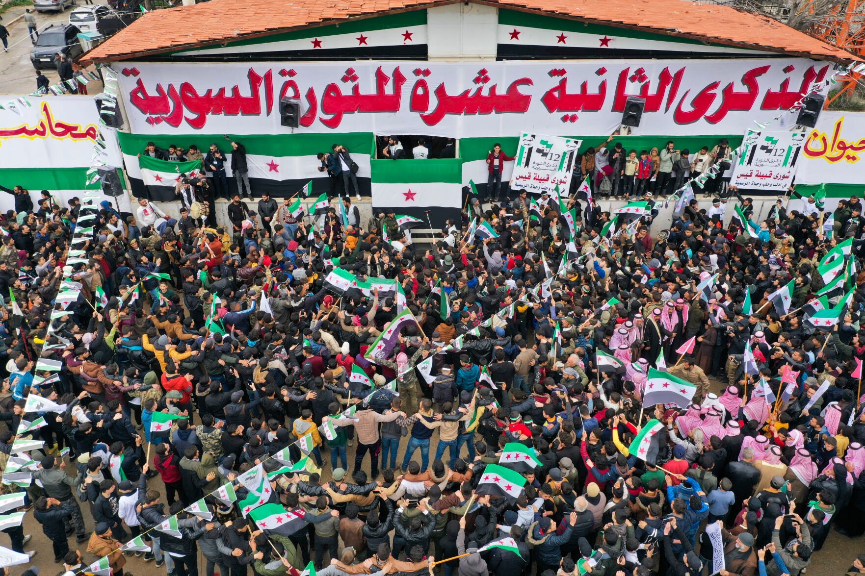 <p>Syrians gather Wednesday to mark the 12th anniversary of the anti-government uprising in the city of Idlib, Syria.</p>
