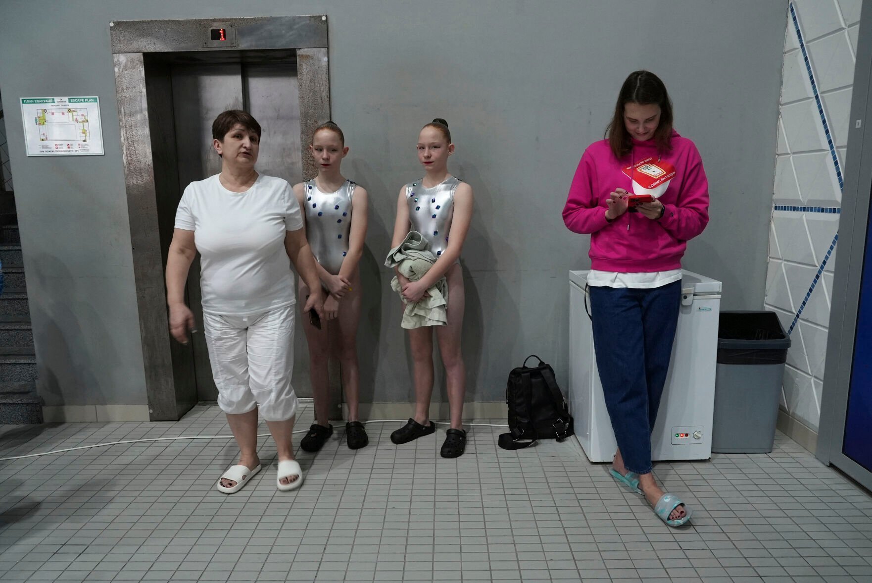 <p>A pair of competitors wait with officials on the sidelines of the Ukrainian national artistic swimming championships Feb. 18 in Kyiv, Ukraine.</p>