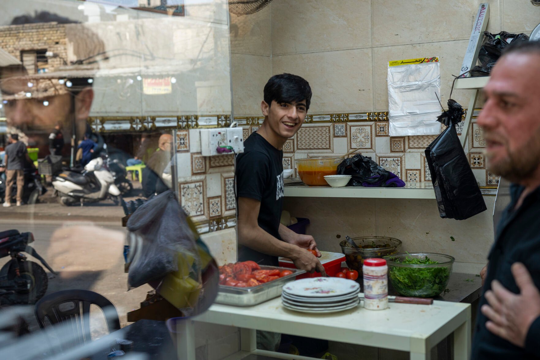 <p>Mohammed Zuad Khaman, center, prepares kebabs at his family's cafe in one of Baghdad's poorer neighborhoods along King Ghazi Street on Monday, Feb. 27, 2023. Khaman is a talented footballer, but he says he cannot get an opportunity to play in any of Baghdad's amateur clubs because he does not have any "in" with the militia-related gangs that control sports teams in the city. (AP Photo/Jerome Delay)</p>