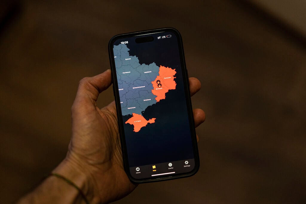 <p>A man takes a photo of his smartphone Monday in Kyiv, Ukraine, showing the "Air Alert" application which shows regions currently under Russian rocket attacks. </p>