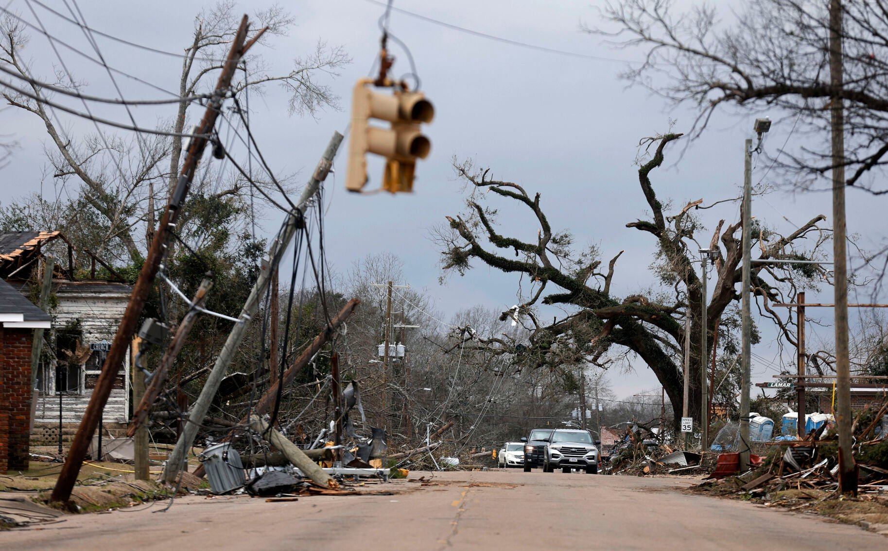 <p>Cars carefully navigate around downed trees and power lines Jan. 13 on Chestnut Boulevard in Selma, Ala., after a tornado passed through the area the day before.</p>
