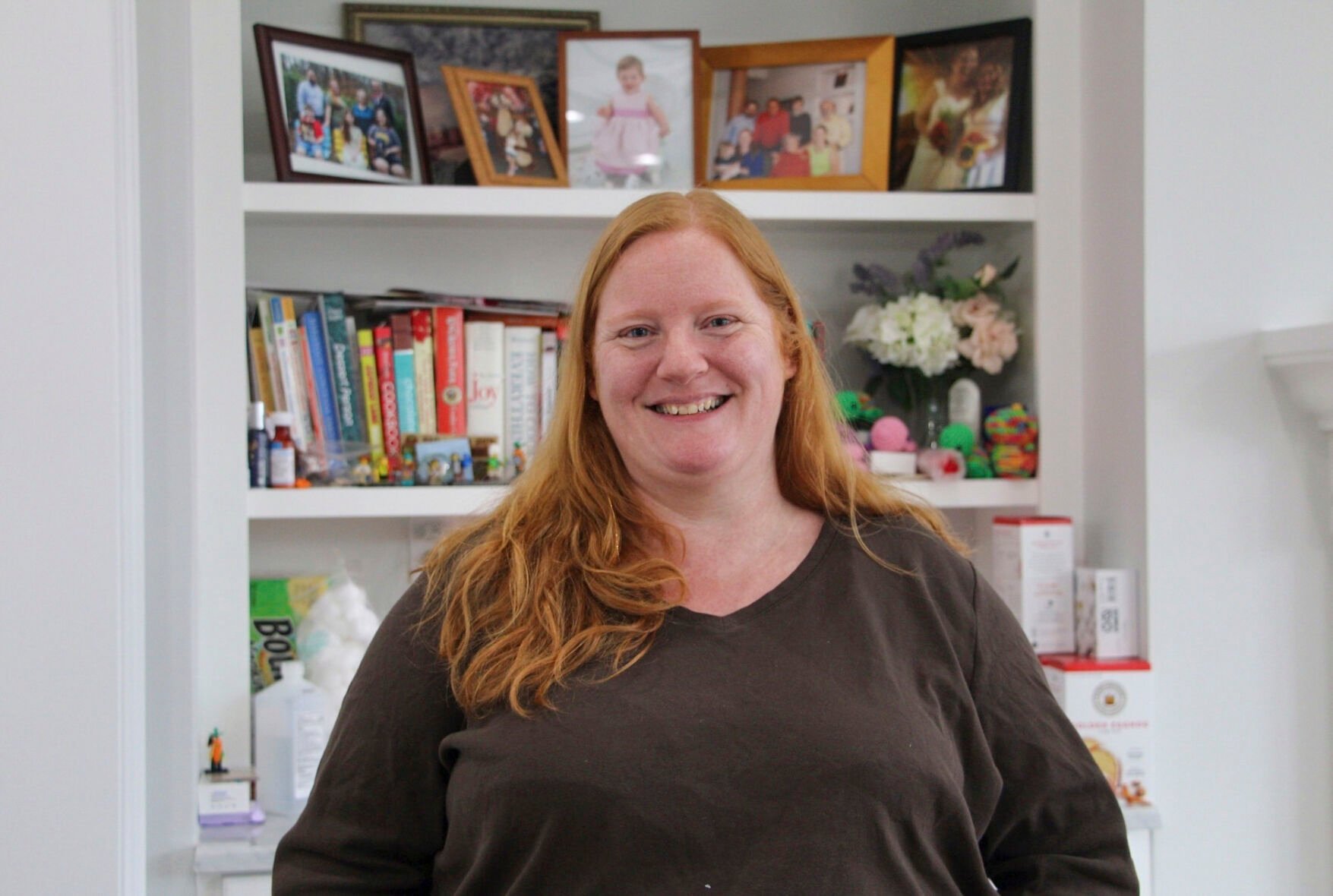 <p>Renee Sekel, the mother of a nonbinary teenager, poses for a portrait in front of family photos at her home Feb. 27 in Cary, N.C.</p>