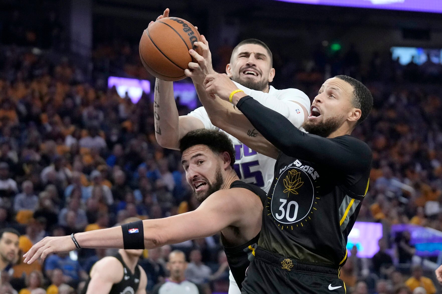 <p>Kings center Alex Len, top, reaches for the ball over Warriors guard Klay Thompson, left, and guard Stephen Curry during the first half of Thursday's first-round game in San Francisco.</p>