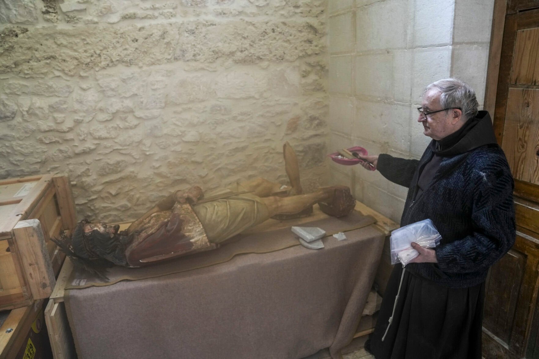 <p>A priest stands by a damaged statue of Jesus in the Church of the Flagellation on Feb. 2 in Jerusalem's Old City.</p>