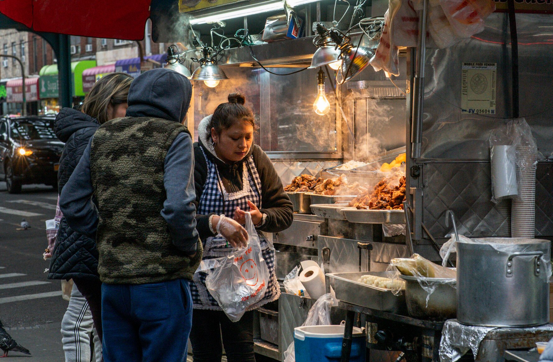 <p>People buy food from a street cart attended by an Ecuadorian vendor Feb. 27 in the Queens borough of New York. </p>
