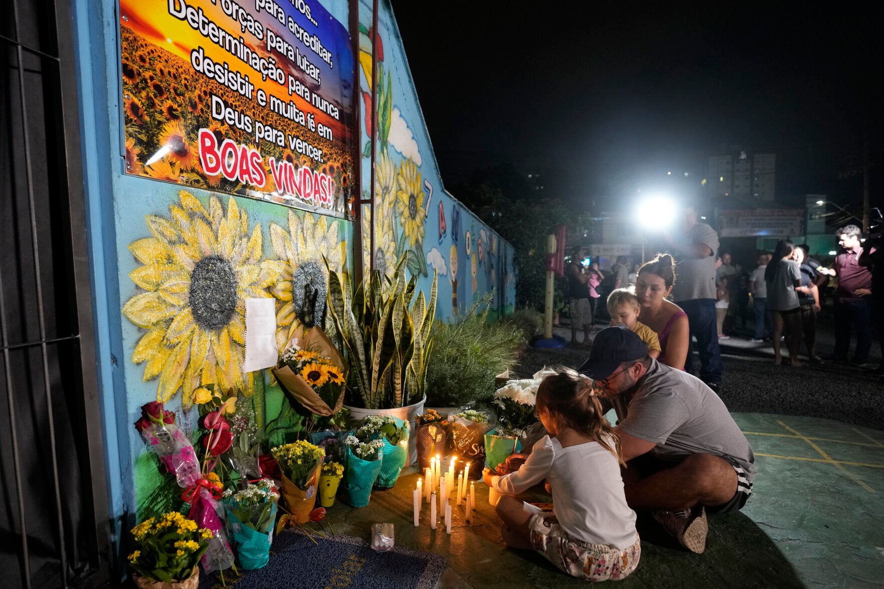 <p>A family lights a candle April 5 at a makeshift memorial at the Cantinho do Bom Pastor day care center after a fatal attack on children in Blumenau, Brazil.</p>