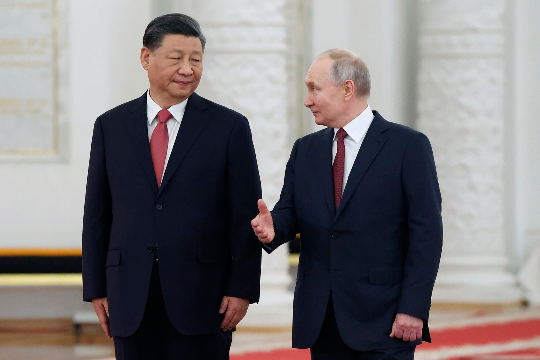 <p>Russian President Vladimir Putin, right, speaks to Chinese President Xi Jinping on March 21 as they attend an official welcome ceremony at The Grand Kremlin Palace in Moscow.</p>