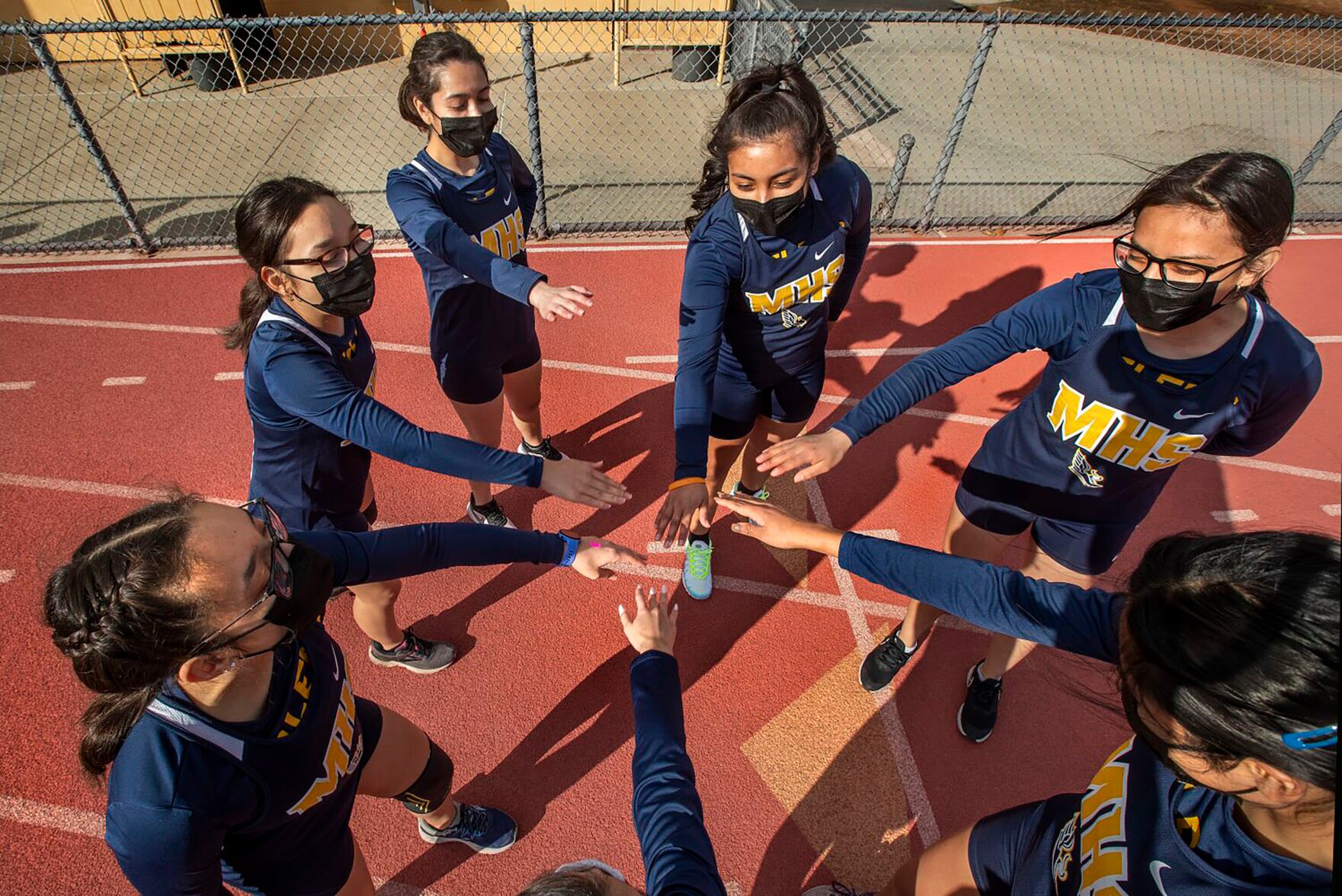 <p>Members of the Montebello High School girls cross country team are careful not to touch hands while wearing masks as they huddle up before a recently home meet in California.</p>