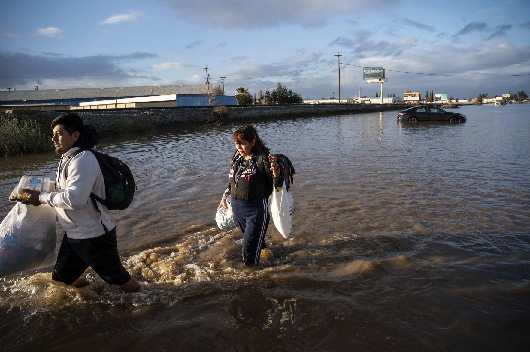 <p>FILE - Angeles Molina carries belongings from her flooded Merced, Calif., home on Jan. 10, 2023. (AP Photo/Noah Berger, File)</p>