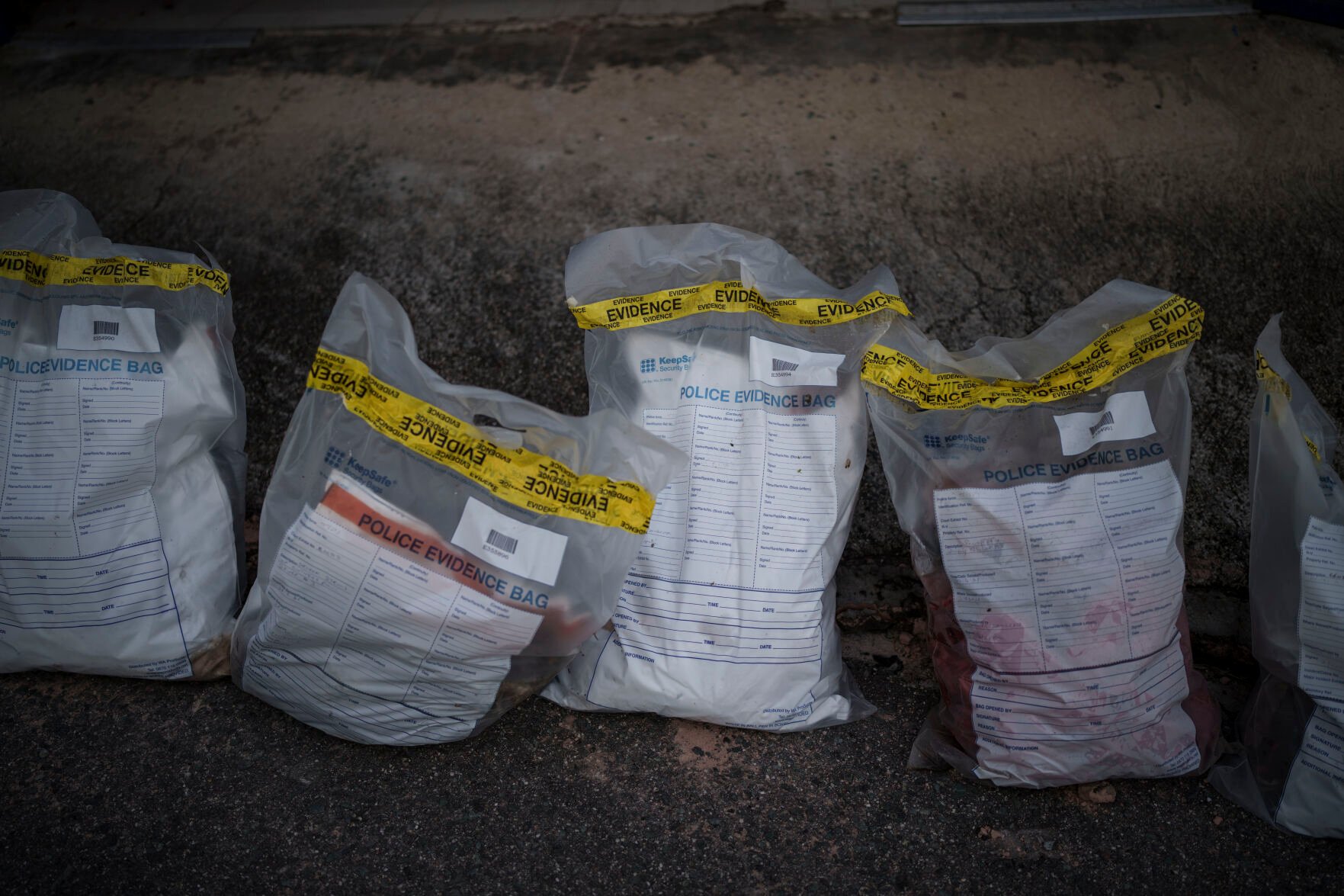 <p>Police evidence bags containing clothing and other items found on a Mauritanian boat are laid out in January 2022 at the Scarborough police station in Tobago, Trinidad and Tobago. An AP investigation has found that the boat had departed the port town of Nouadhibou in Mauritania, Africa, more than four months earlier with 43 migrants aboard.</p>