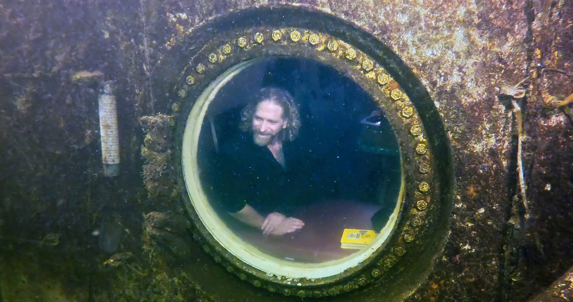 <p>In this photo provided by the Florida Keys News Bureau, diving explorer and medical researcher Dr. Joseph Dituri peers out of a large porthole, Saturday, May 13, 2023, at Jules' Undersea Lodge positioned at the bottom of a 30-foot-deep lagoon in Key Largo, Fla. </p>