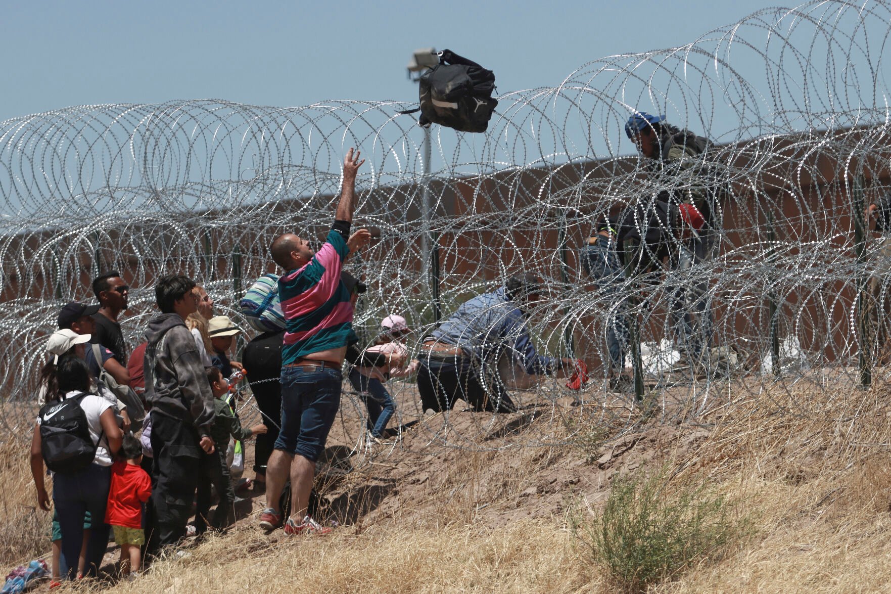 <p>Migrants cross a barbed-wire barrier at the US-Mexico border May 11 as seen from Ciudad Juarez, Mexico.</p>
