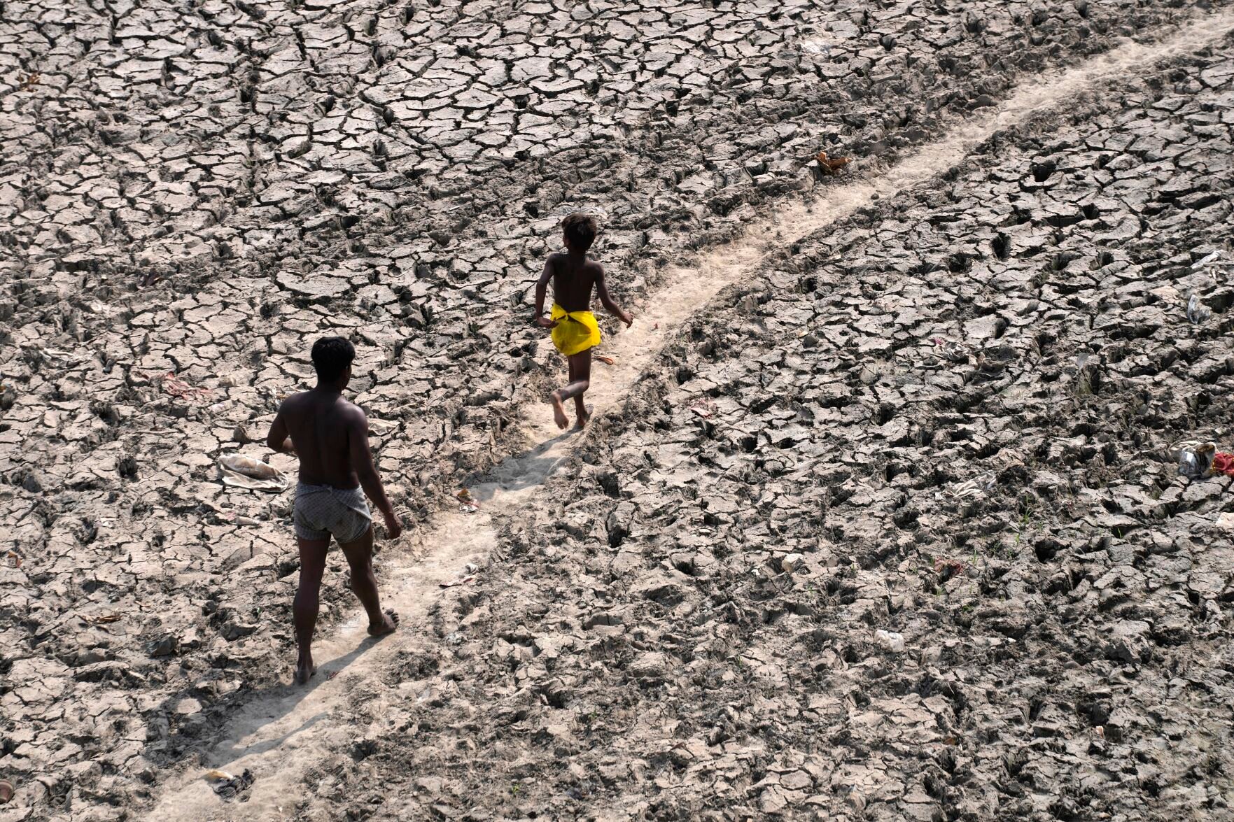 <p>A man and a boy walk across an almost dried up bed of river Yamuna following hot weather in New Delhi, India, on May 2.</p>