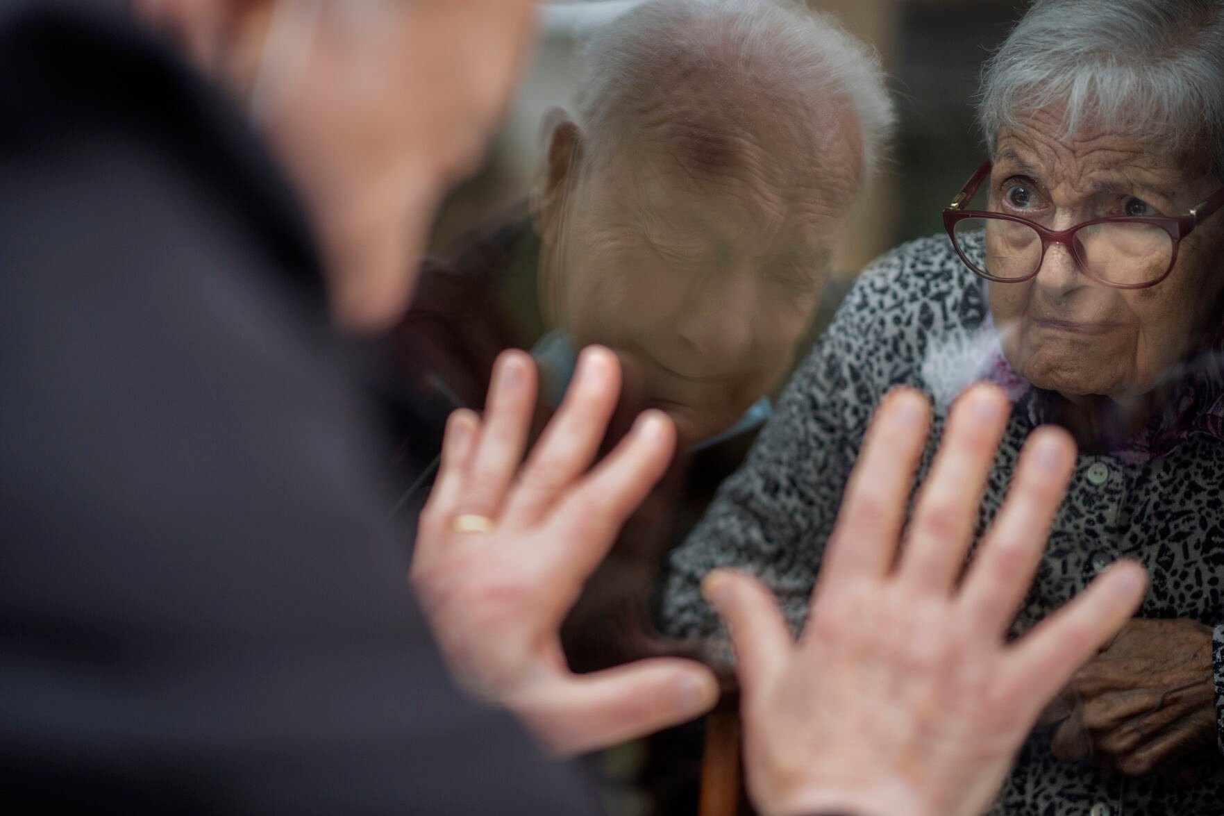 <p>Javier Anto, 90, reacts April 21, 2021, in front of his wife, Carmen Panzano, 92, through the window separating the nursing home from the street in Barcelona, Spain.</p>
