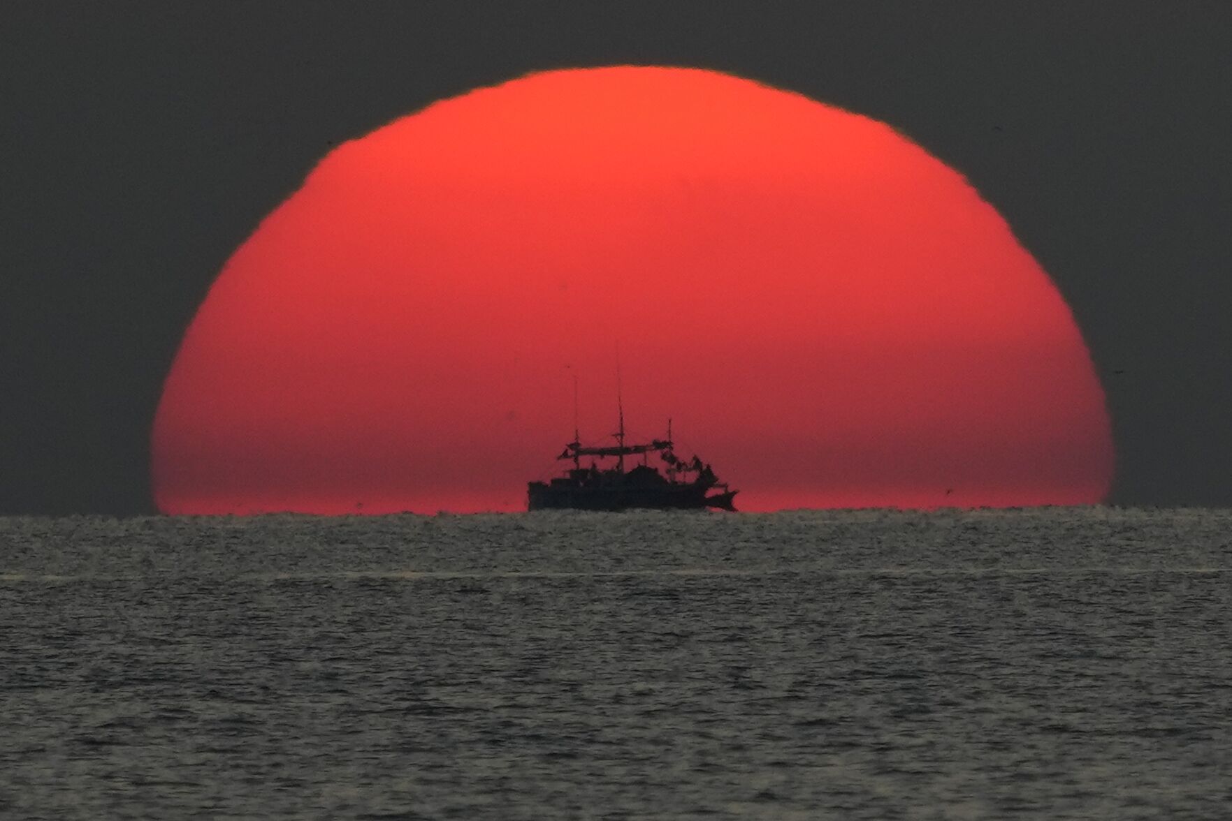 <p>A fishing boat passes by a setting sun in the Sulu Sea, as seen from the Philippine Coast Guard ship BRP Malabrigo on April 18 while it heads to Philippine-occupied areas in the nearby South China Sea.</p>