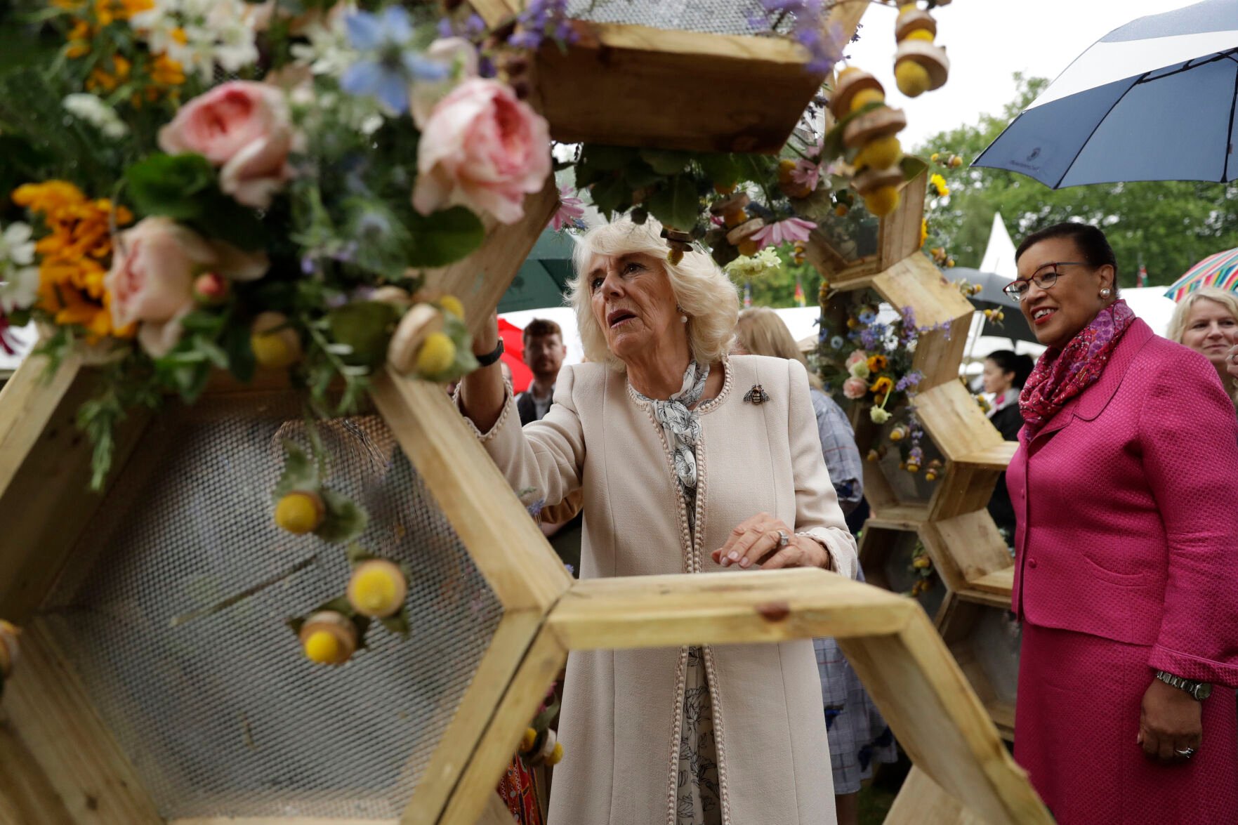 <p>Britain's Camilla Duchess of Cornwall places a bee made of flowers, birch wood and leaves on a display June 12, 2019, at a garden party at Marlborough House in London.</p>