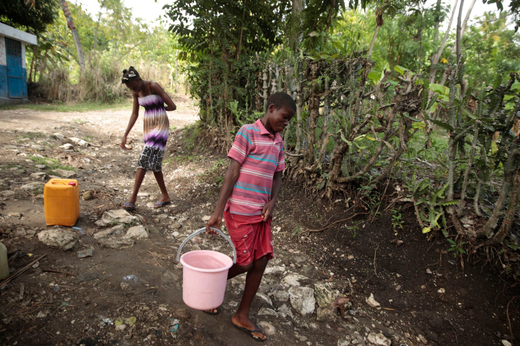 <p>Siblings Mylouise Veillard, left, and Myson walk home with water they collected from a well, for cooking, cleaning and drinking, May 25 in a rural area of Saint-Louis-du-Sud, Haiti.</p>