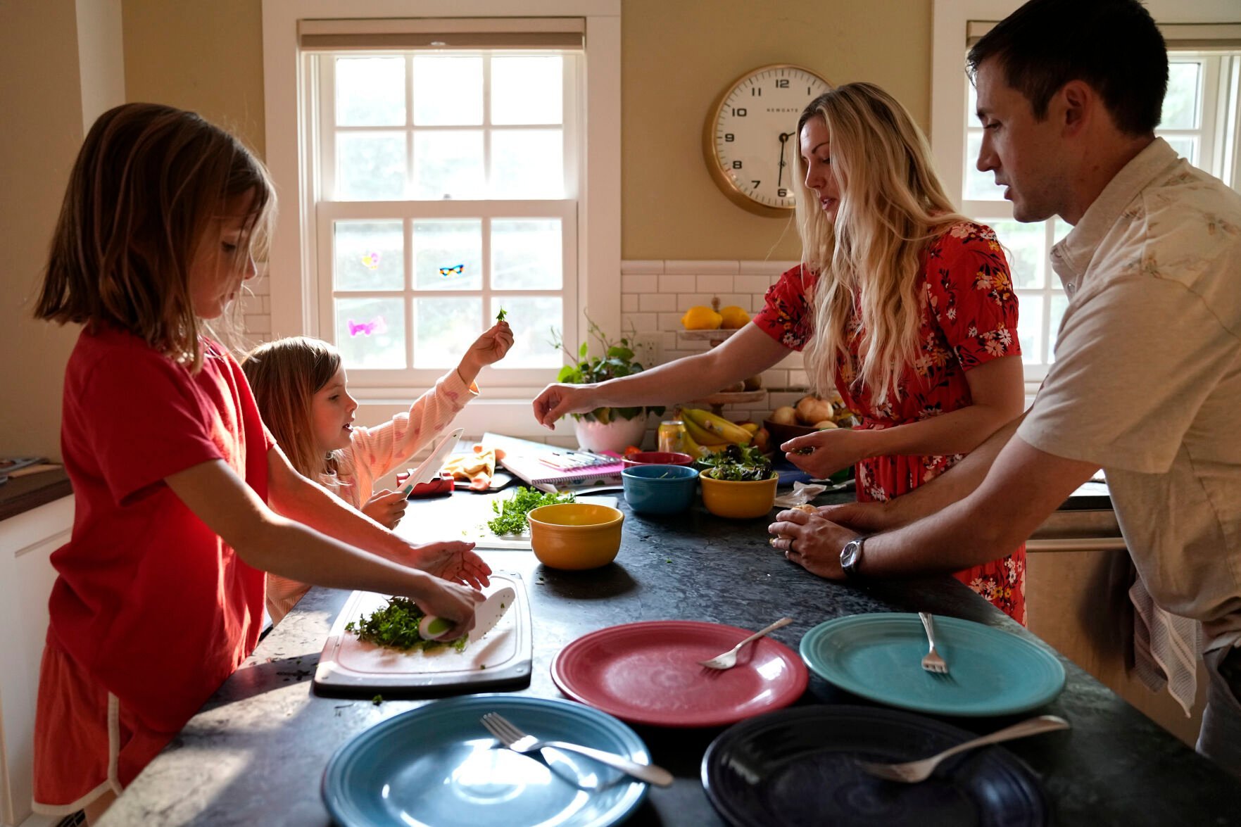 <p>OB-GYN Dr. Kylie Cooper prepares dinner with her husband, Nick, and daughters, Cleo, left, and Hazel on June 15 in Minnesota. The family is settling into their new house after moving and looking for new friends. “Basically,” Cooper said, “we’re trying to find what we had in Idaho.”</p>