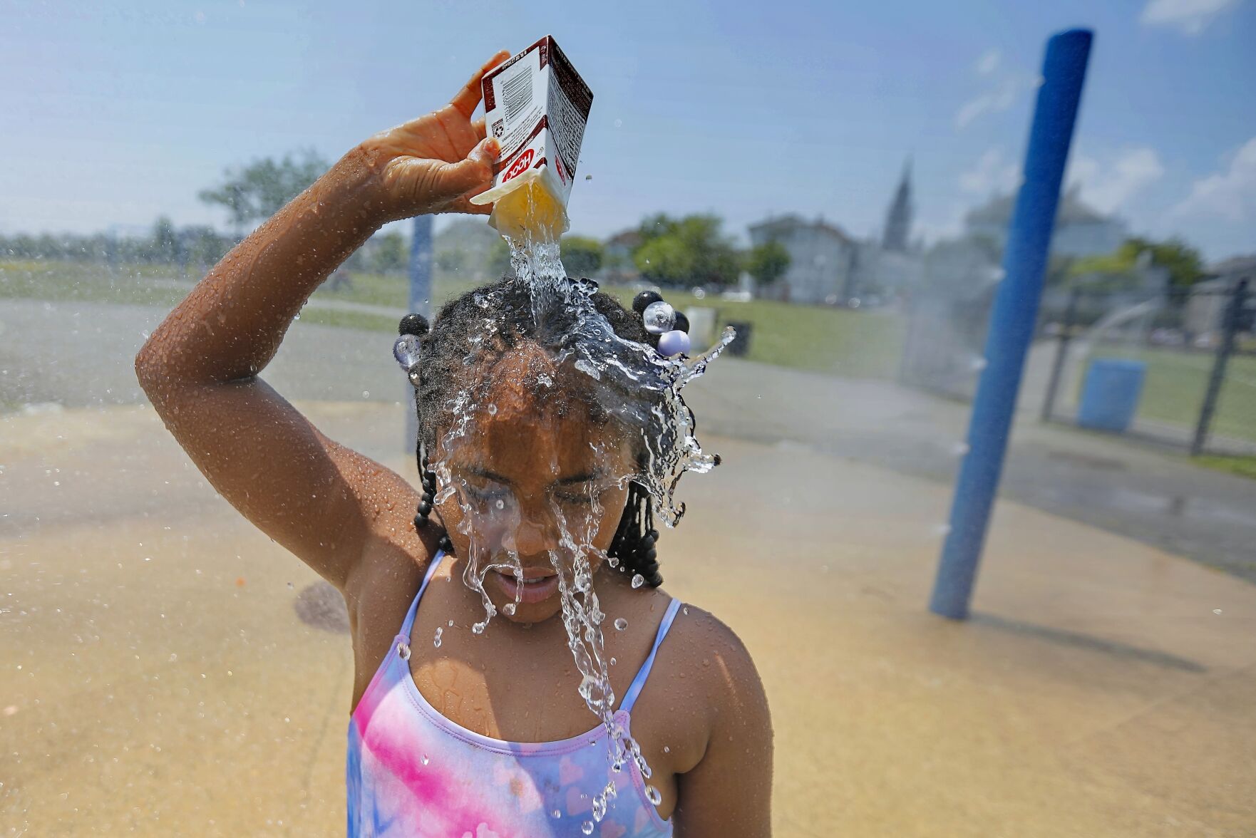 <p>Ja-Veah Cheney, 9, pours water over her head, taking shelter from the sweltering heat Wednesday at the splash pad station at Riverside Park in New Bedford, Mass.</p>