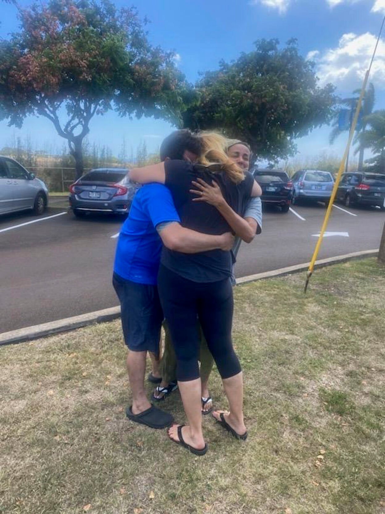 <p>This Aug. 9, 2023 photo taken by his stepfather Mike Eilers and provided by Mike Cicchino shows Mike Cicchino, left, and his wife Andreza, right, hugs Mike's mother Susan Ramos as they were reunited at shelter in Maui, Hawaii. </p>