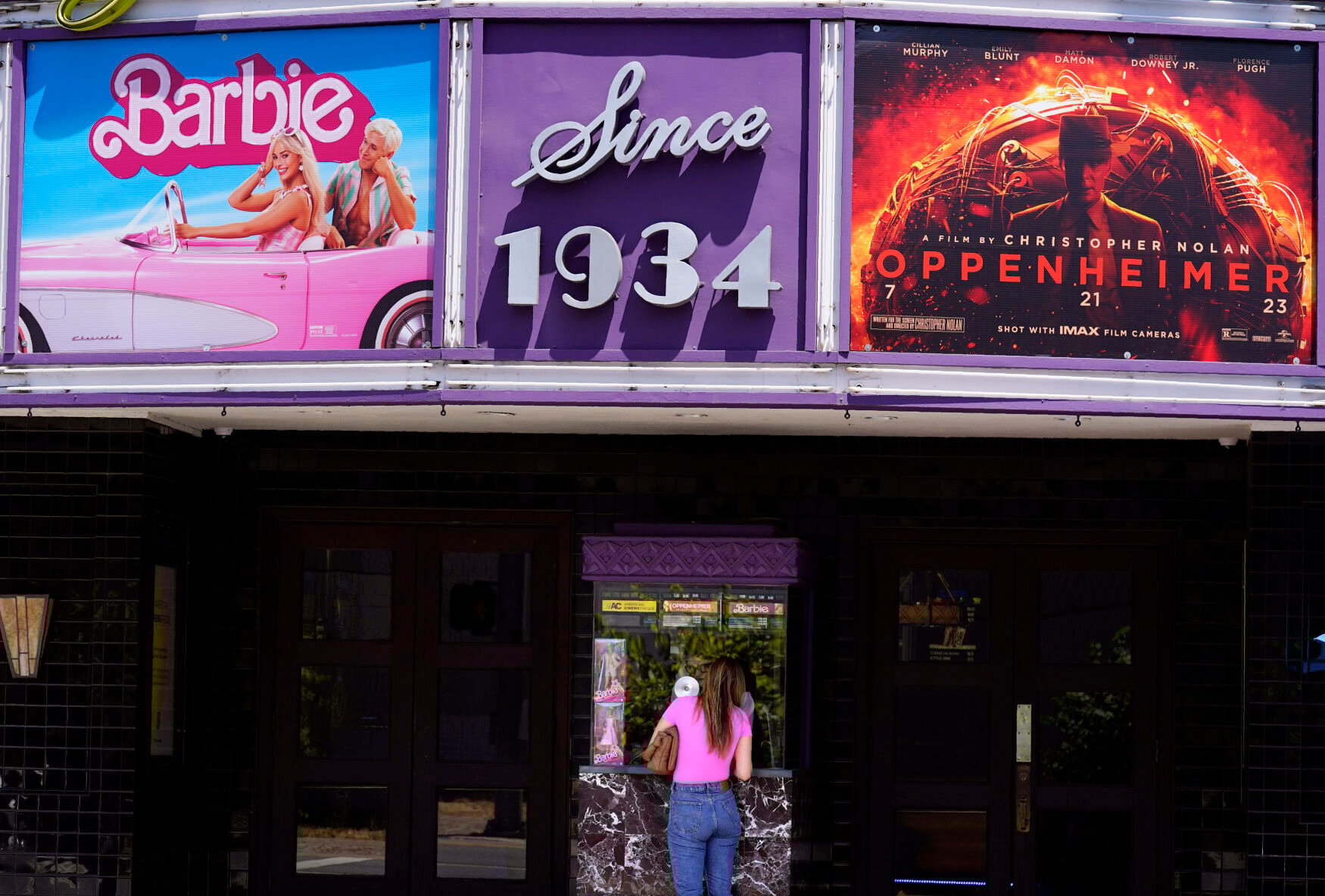 <p>A patron buys a movie ticket underneath a marquee featuring the films "Barbie" and "Oppenheimer" at the Los Feliz Theatre, Friday, July 28, 2023, in Los Angeles. (AP Photo/Chris Pizzello)</p>