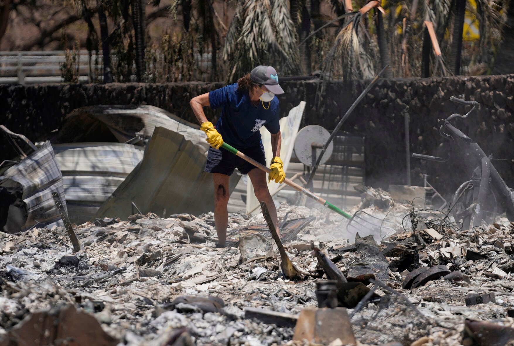 <p>A woman digs through rubble of a home destroyed by a wildfire Aug. 11 in Lahaina, Hawaii. </p>