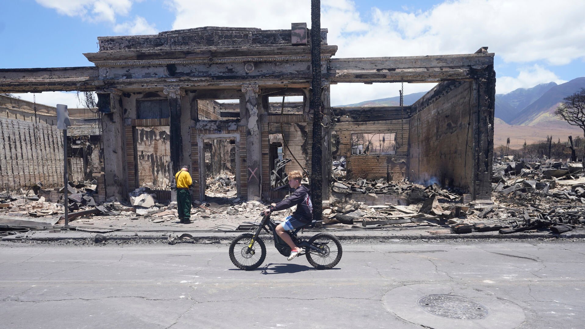 <p>A boy rides along Main Street past wildfire damage on Friday, Aug. 11, 2023, in Lahaina, Hawaii.</p>