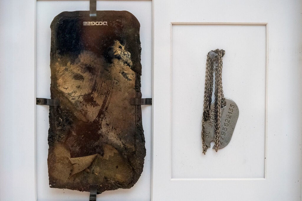<p>The burnt mobile phone and military identification tag of Ivanna Rumiantseva's father Illich, who are part of her e-diary, are displayed at the War Diaries exhibition, showcasing the personal diaries of Ukrainian children who have witnessed the war, hosted by the Amsterdam city hall , Netherlands, Thursday, Aug. 17, 2023. </p>