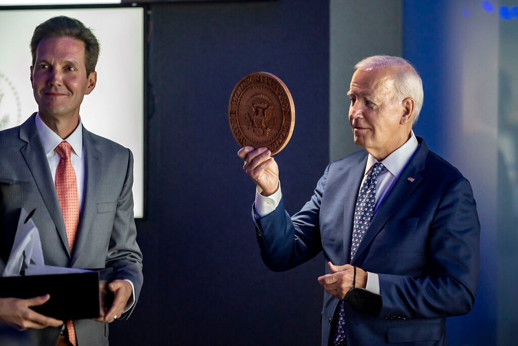 <p>In this image provided by the White House, President Joe Biden holds a wooden presidential seal presented to him by Situation Room director Marc Gustafson, left, as tours the "watch floor" in renovated White House Situation Room complex, Sept. 5, 2023, in the West Wing of the White House in Washington. </p>
