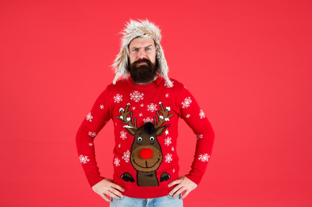 Join Holiday Party Craze And Host Ugly Christmas Sweater Party. Winter Party Outfit. Buy Festive Clothing. Sweater With Deer. Hipster Bearded Man Wear Winter Sweater And Hat. Happy New Year