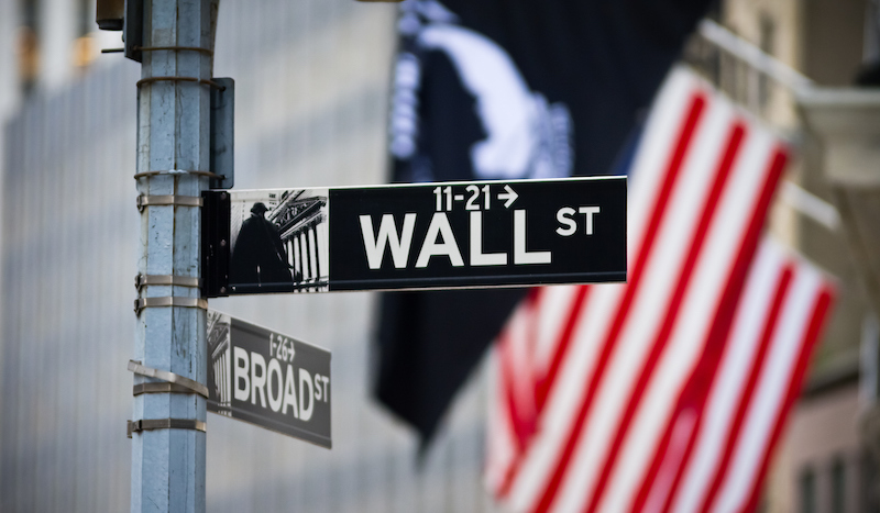 Wall Street Sign With American Flag In The Financial District Of Lower Manhattan