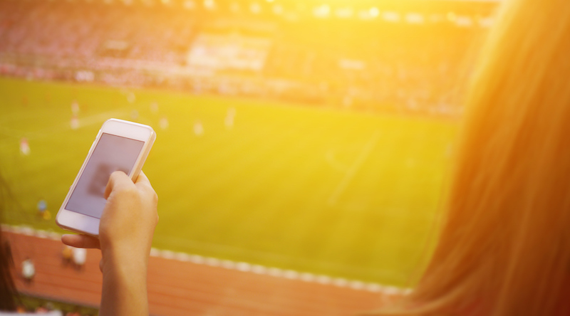 Women Are Using Smart Phone On The Soccer Stadium.