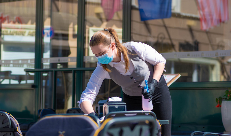 Waitress With A Mask Disinfects The Table