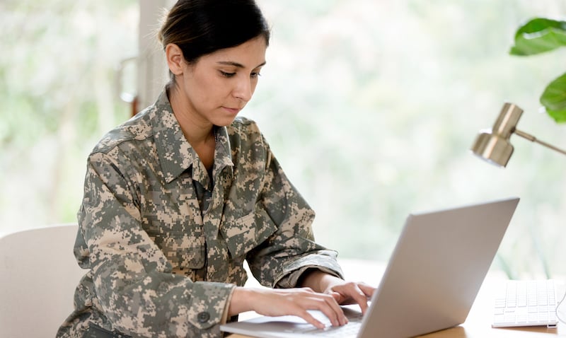 Mid Adult Female Soldier Works On Laptop At Home