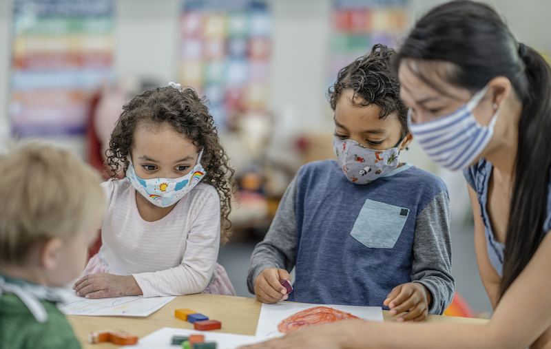 Group Of Children Colouring While Wearing Masks